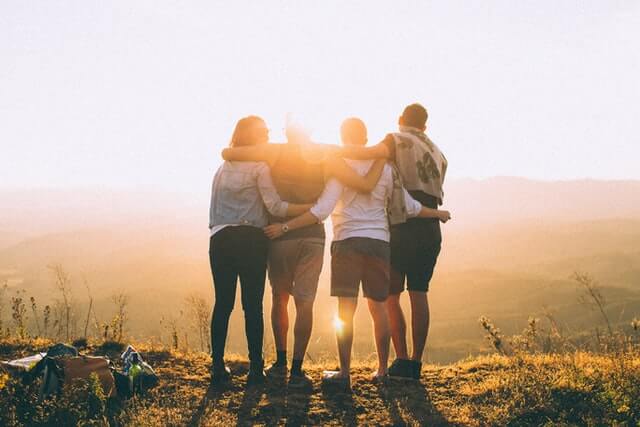 Multi-ethnic millenial group of friends taking a selfie photo with mobile phone on rooftop terrasse at sunset